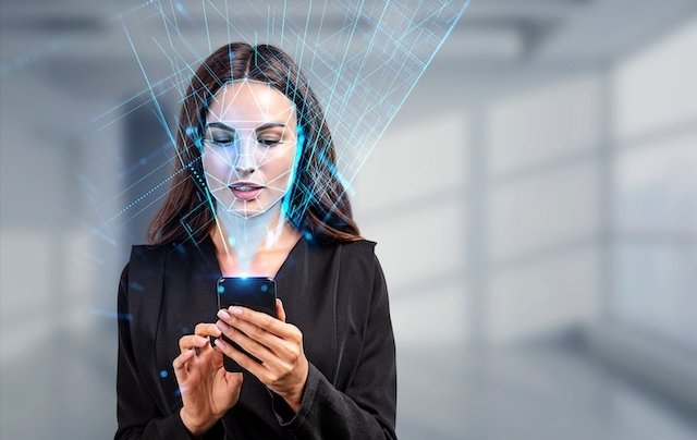 Businesswoman with phone in hands, biometric verification and face detection. Unlocking smartphone with facial scanner. Concept of face id and high tech technology